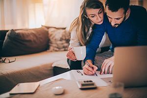 Couple reviewing finances at home with computer