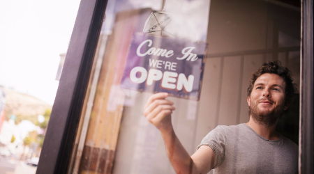 Man turning Open sign over in business window