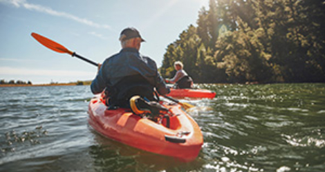 Couple in kayaks passing trees