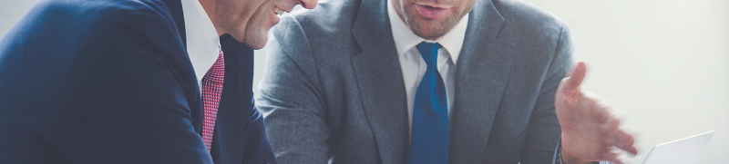 Men in suits discussing business by laptop
