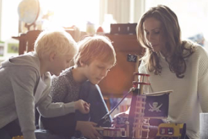 A woman playing with two young boys at home
