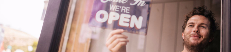 Man turning Open sign over in business window