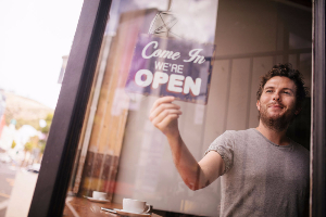 Man turning Open sign over in business window