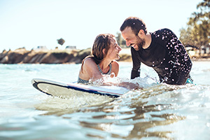 Couple in ocean on surfboard