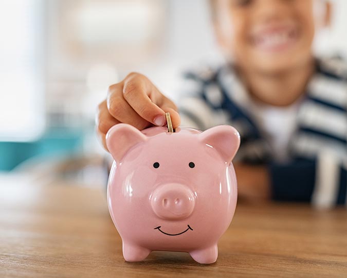 Child putting coins into piggy bank