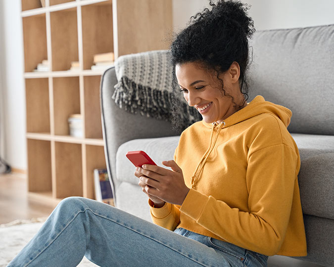 Woman sitting in her home, looking at her phone